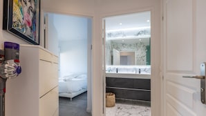 A modern hotel room with a bed, a bathroom with a marble floor, and a large mirror.