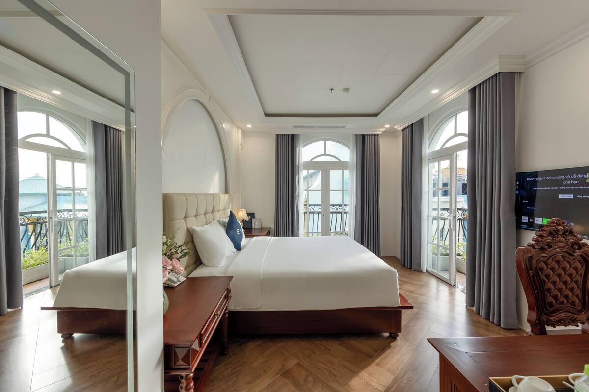 A spacious hotel room with a large bed, a wooden desk, and a television.