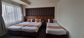 Een hotelkamer met twee bedden, een houten hoofdbord en een nachtkastje met een lamp.