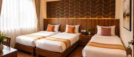 A hotel room with two beds, a wooden headboard, a desk, and a large window with curtains.