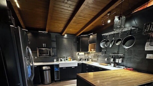 Una cocina moderna con una isla central, muebles negros y electrodomésticos de acero inoxidable.
