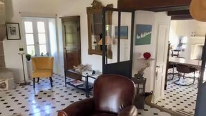 Une pièce comprenant un fauteuil en cuir marron, un fauteuil jaune et un coin repas avec une table et des chaises.