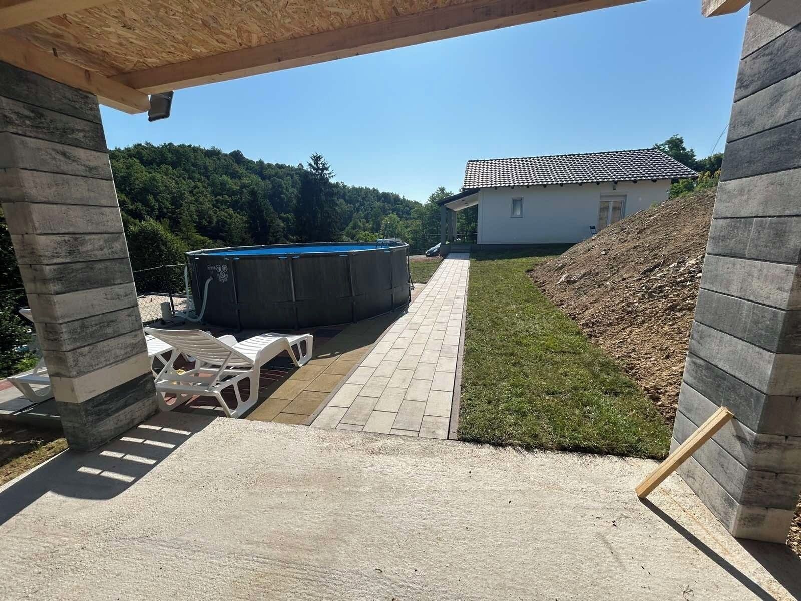 Una zona de pati coberta amb piscina, mobles d'exterior i una casa al fons.