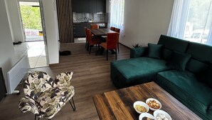 Una sala de estar moderna con una mesa de centro de madera, un sofá verde y un comedor con una mesa y sillas.