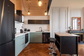 A modern kitchen with a black refrigerator, light blue cabinets, a wooden countertop, and a wooden island with bar stools. - Smartstay - Vue panoramique sur Lyon et la saone (Lyon)