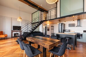Une cuisine moderne avec un îlot central en bois, des tabourets de bar noirs et un escalier menant à un niveau supérieur.