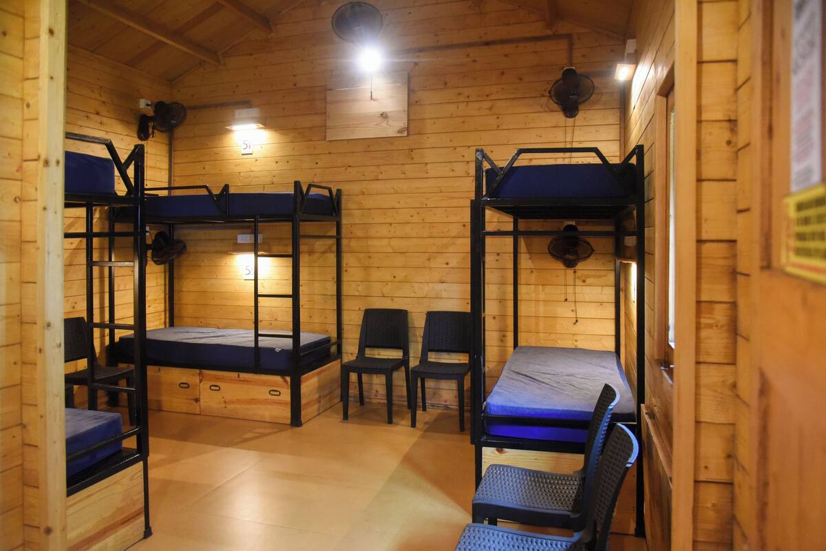 A wooden cabin with bunk beds, chairs, and a clock on the wall.