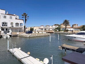 Un port de plaisance avec des bateaux amarrés, un bâtiment blanc doté de balcons et un ciel bleu azur.
