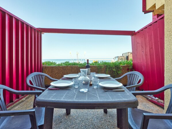 A table set for dining with a view of the sea, surrounded by red walls. - Primavéra by Interhome (Lacanau)