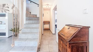 Un interior moderno con una escalera, un mueble de madera y un armario blanco con una planta.