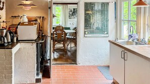 Een keuken met een bakstenen vloer, houten stoelen, een eettafel en een raam met een sterrenkaart.