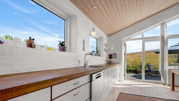 Eine moderne Küche mit Holzausziehtisch, weißen Schränken und einem großen Fenster.