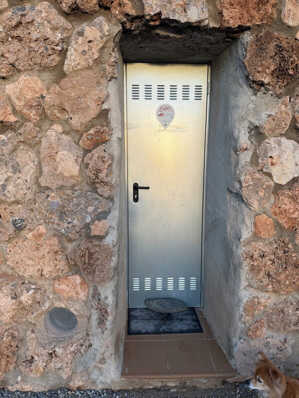 Una porta metallica con un adesivo a forma di cuore, incastonata in un muro di pietra.
