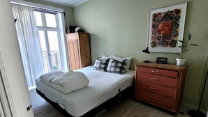 A bedroom with a bed, a dresser, a radiator, a window with curtains, and a painting on the wall. - Best location at Vesterbro and close to subway (Copenhagen v)
