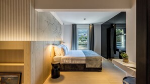 A modern bedroom with a large bed, a side table, a potted plant, and a view of the outdoors. - Beachfront Penthouse Residence (Podstrana)
