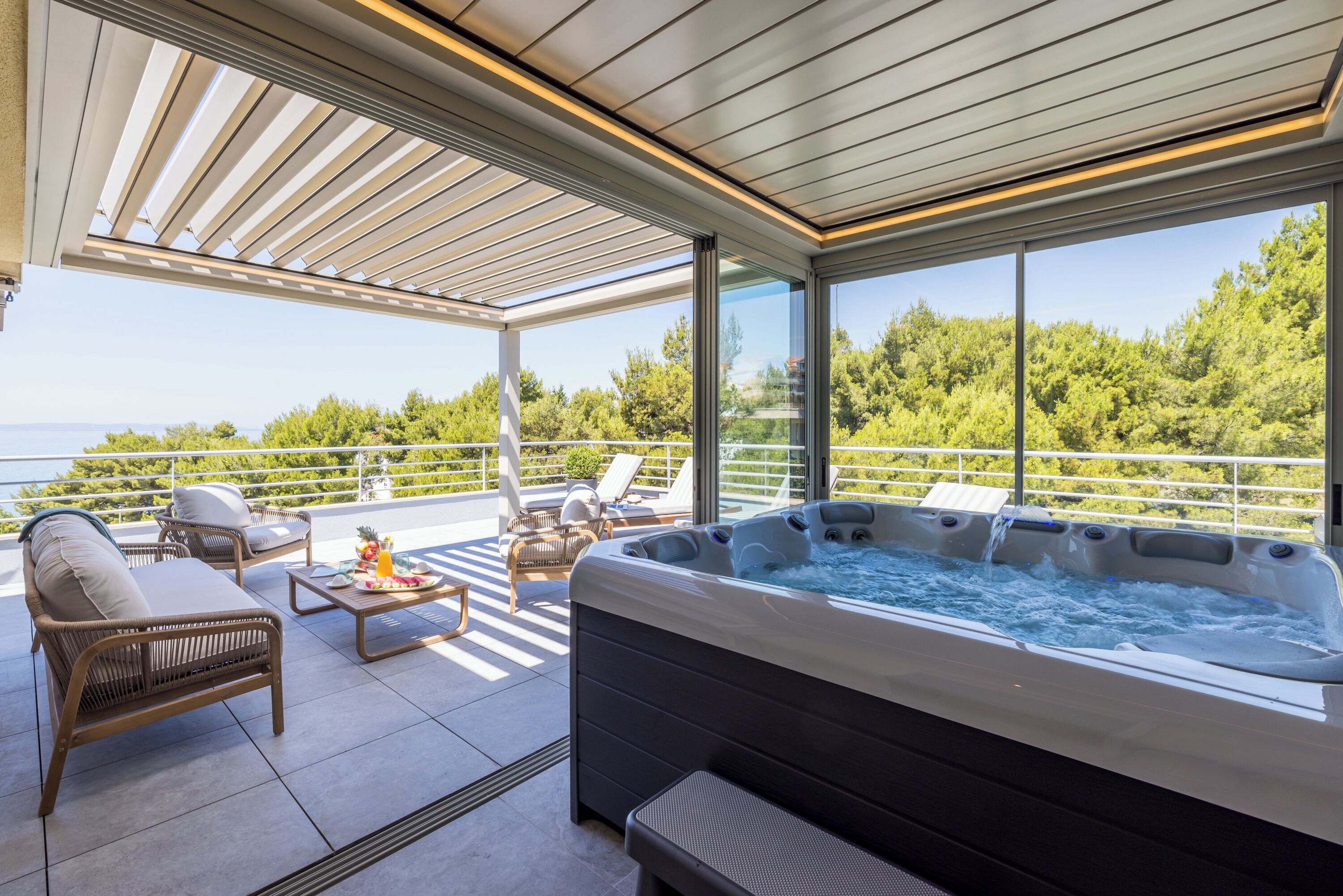 A modern outdoor hot tub area with seating and a view of the sea.