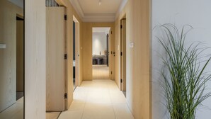 A hallway with wooden doors and a tiled floor leading to a kitchen area. - Beachfront Penthouse Residence (Podstrana)