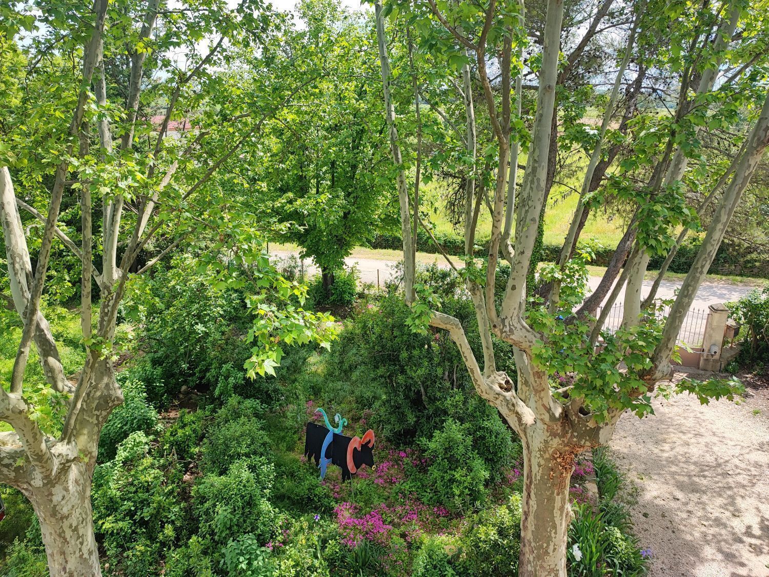 A lush garden with dense foliage and a decorative metal sculpture.