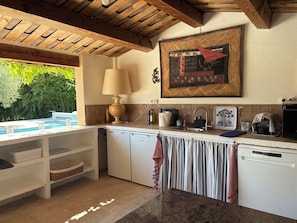 Une cuisine avec un plafond en bois, un grand tableau, un évier et un lave-vaisselle.