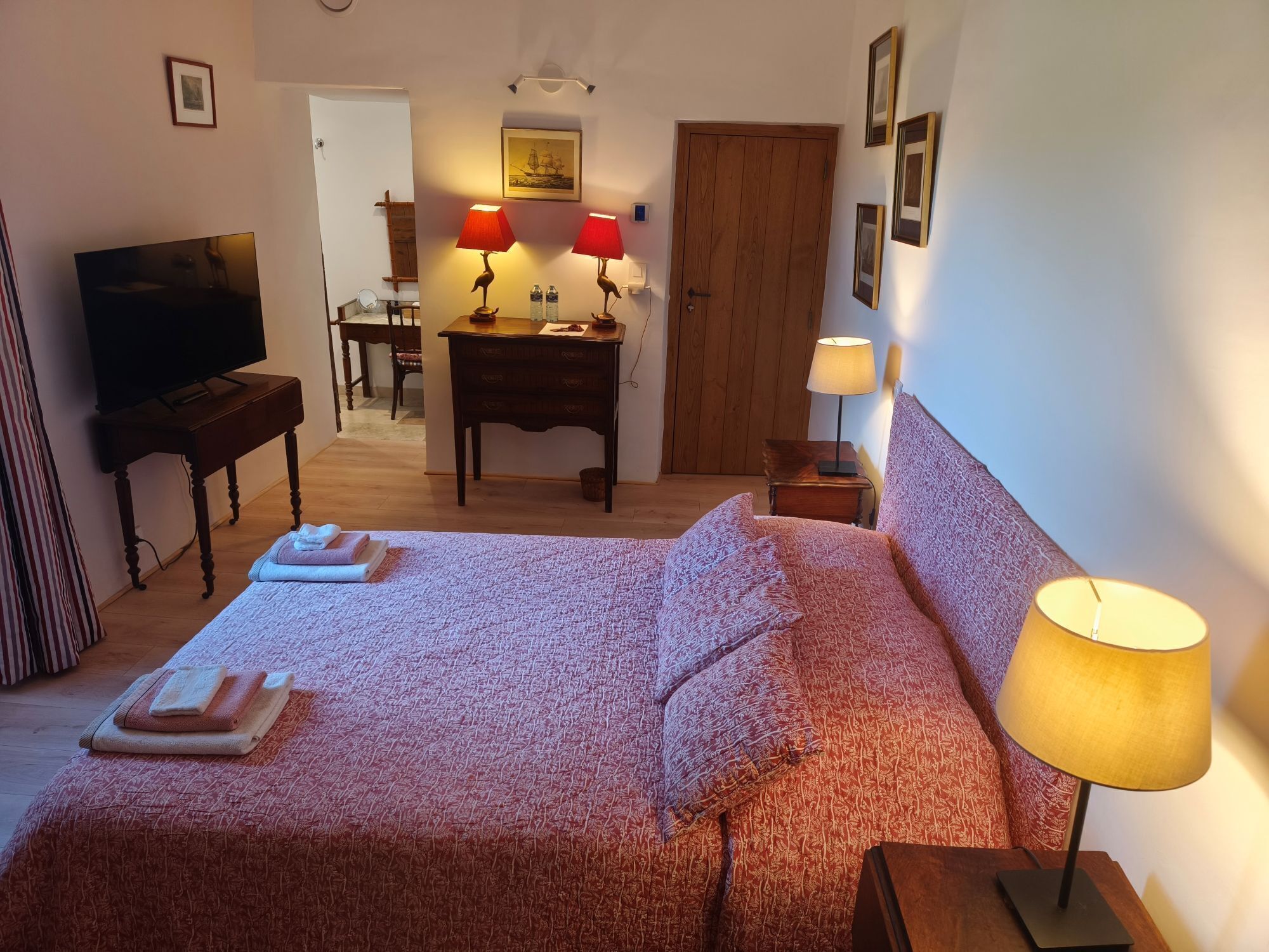 Una habitación de hotel con cama, televisión, escritorio y puerta.