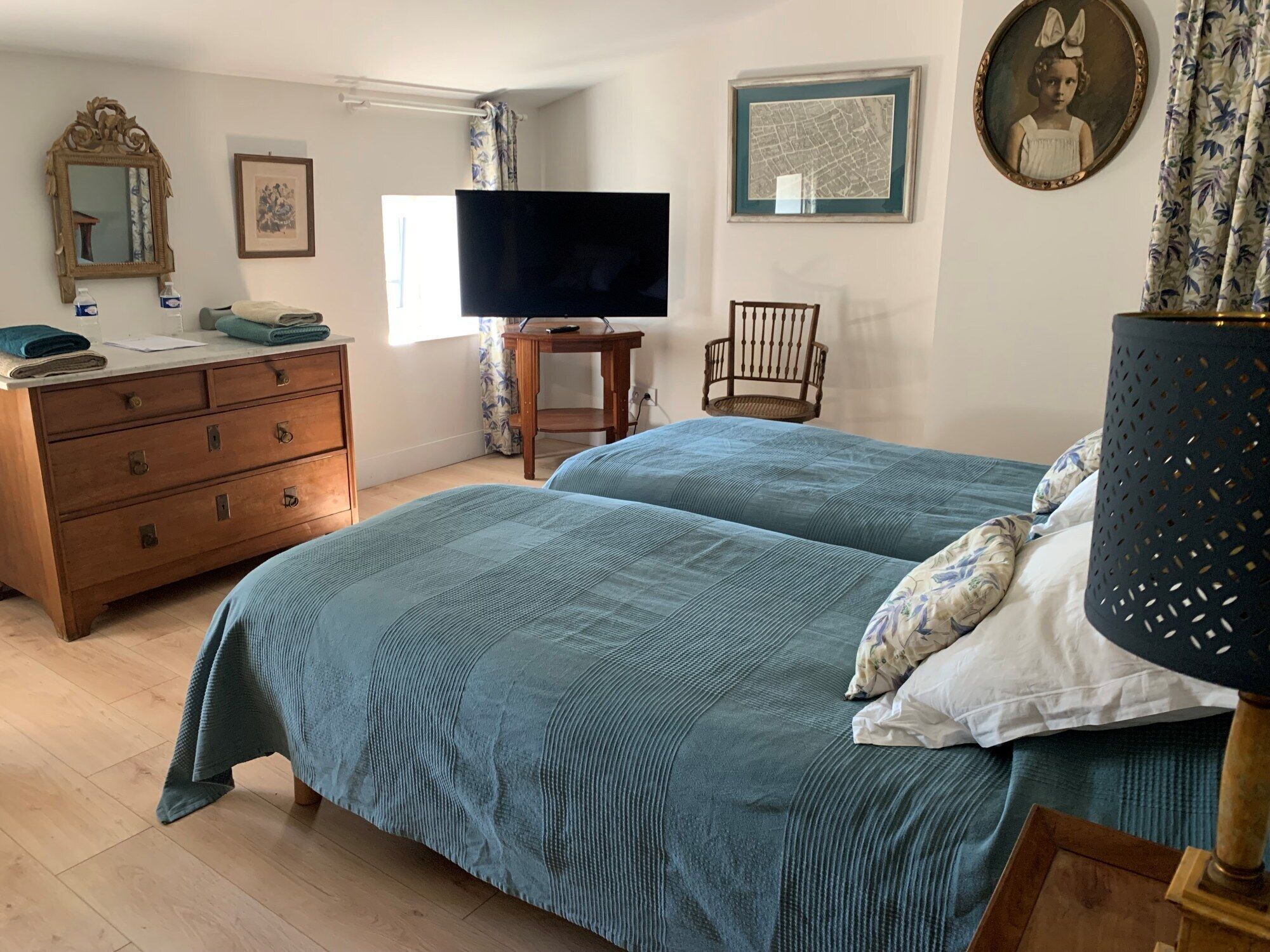 Un dormitorio con dos camas, un aparador de madera, un televisor y una silla.
