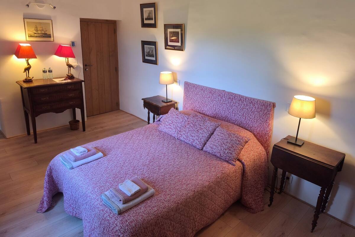 A neatly arranged bedroom with a bed, two bedside tables, a wooden dresser, and wall-mounted lamps.