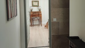 A hallway leading to a dining area with a wooden table and chairs, a framed picture on the wall, and a cat on the floor. - Magnanerie de Sainte Croix (Saint-Hippolyte-de-Caton)