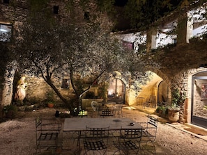 An outdoor patio with a table and chairs, surrounded by stone walls and potted plants. - Magnanerie de Sainte Croix (Saint-Hippolyte-de-Caton)