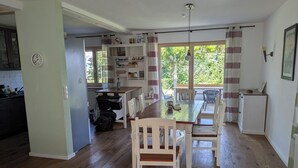 A spacious kitchen with wooden flooring, a dining area with a wooden table and chairs, and a view of greenery through large windows. - Vacation apartment Ludwigshöhe (Weißenburg)