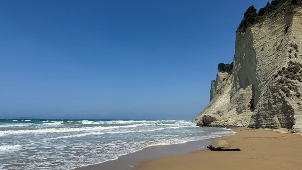 A beach with a sandy shore and a rocky cliff.