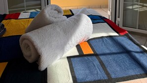 A room with a bed, a window with a view of a balcony, and a towel on the bed.