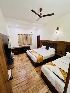 A hotel room with a large bed, a smaller bed, a TV, a ceiling fan, and a wall-mounted light fixture. - Park view Yelagiri (Yelagiri)