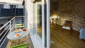 A balcony with a table set for two, a wooden deck, and a stone wall interior. - -STONE-Maison de Ville à Concarneau (Concarneau)