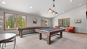 Une table de billard dans une pièce dotée de grandes fenêtres, une table à manger et une chaise rouge.