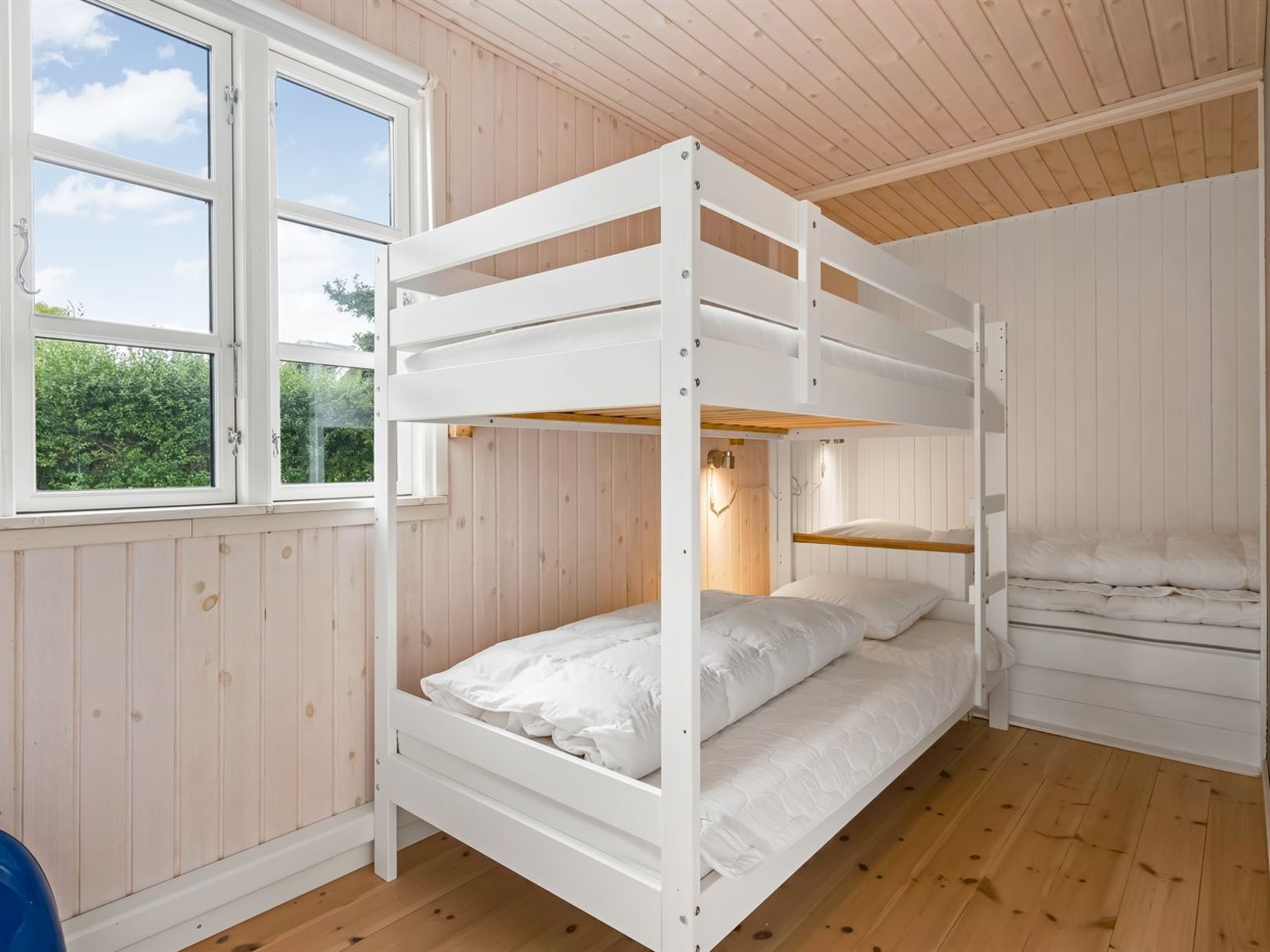 Habitación con literas, ventana, paredes de madera y suelo de madera.