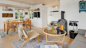 A cozy living room with a fireplace, wooden furniture, and a dining area with a view of the outdoors.
