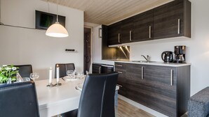 Une cuisine moderne avec des meubles de couleur bois foncé, un plan de travail blanc et un coin repas comprenant une table et des chaises.