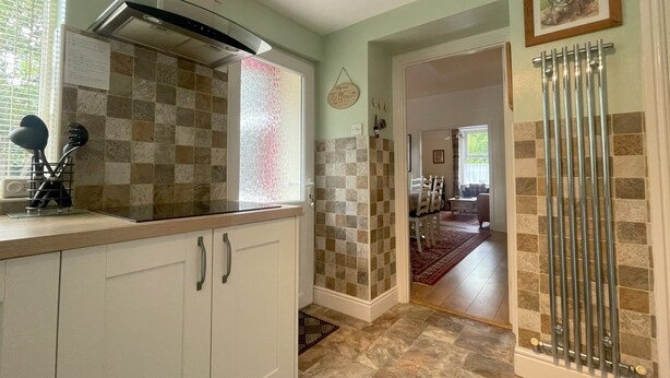A kitchen with white cabinets, a stainless steel range hood, and a checkered backsplash.