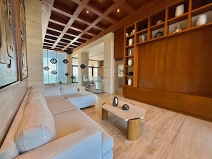 A modern living room with a light-colored sofa, a wooden coffee table, and a built-in shelf with decorative items. - Condo On the Malecón with Views By GPSRentas (Mazatlan)