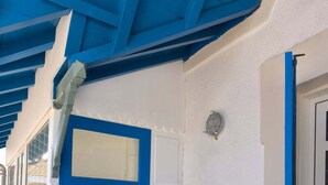 Eine blaue Tür mit Fenster, weiße Wände und ein Fliesenboden.