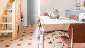Eine kleine Küche mit einer Holztreppe, einem Esstisch mit Stühlen und einer Waschmaschine.