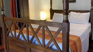 Un letto a baldacchino con struttura in legno e copripiumino bianco.