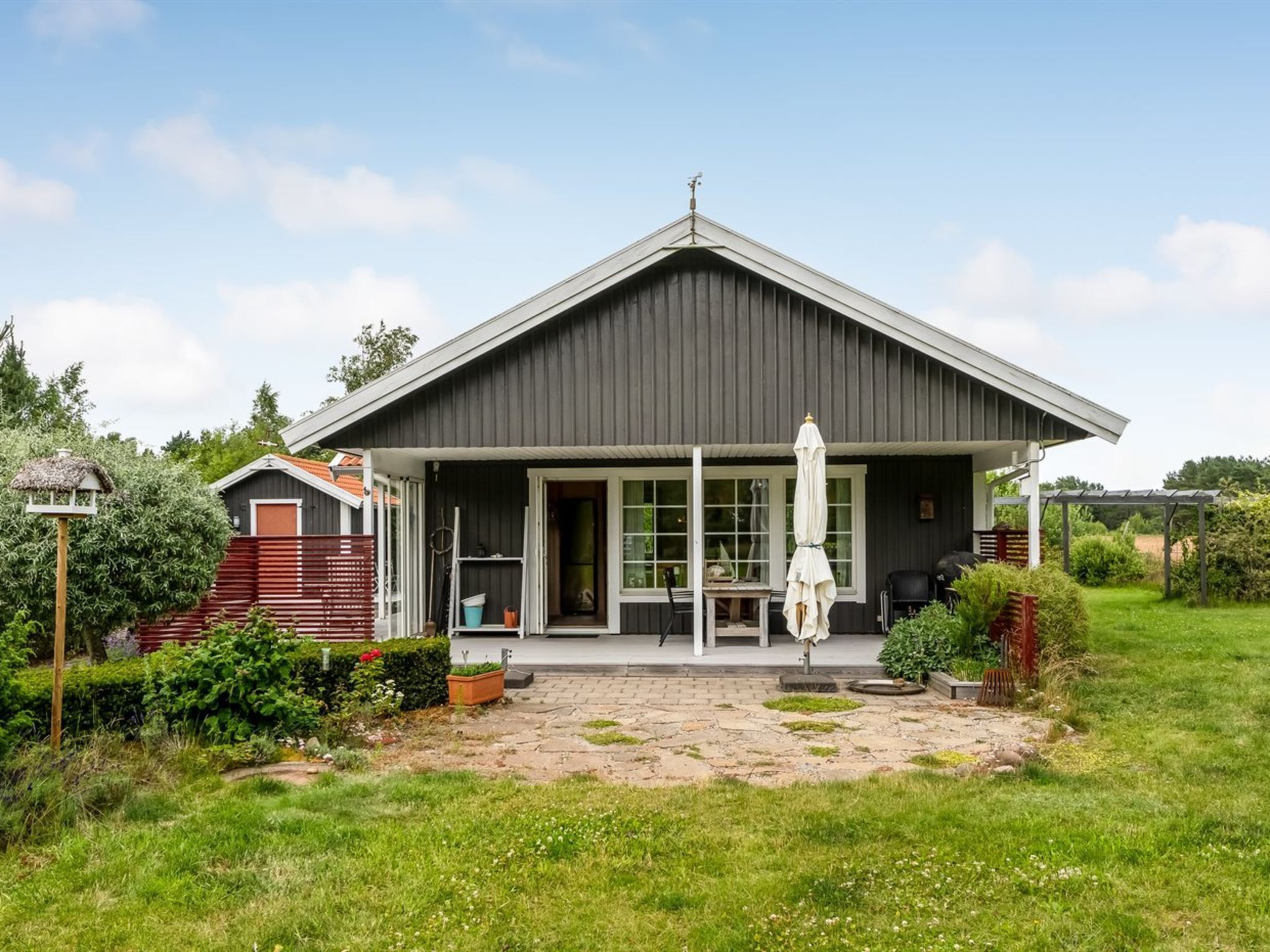 A modern house with a dark roof, a covered porch, and a garden.