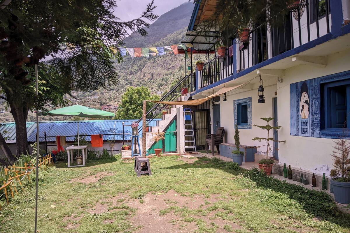 Un patio con una escalera que lleva a un balcón, rodeado de plantas en macetas y un paraguas verde.