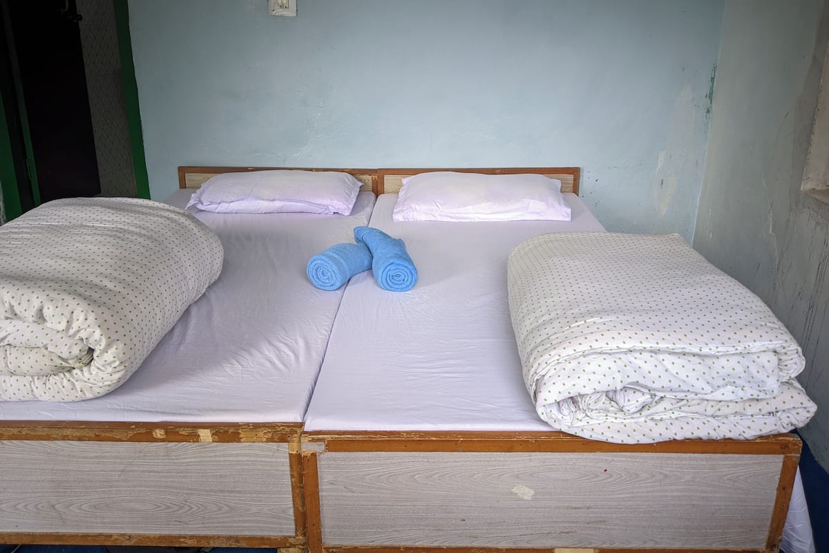 Una cama individual con ropa blanca de cama y dos toallas enrolladas.