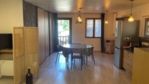 Una cocina moderna con comedor, armarios de madera, refrigerador y una ventana con cortinas.