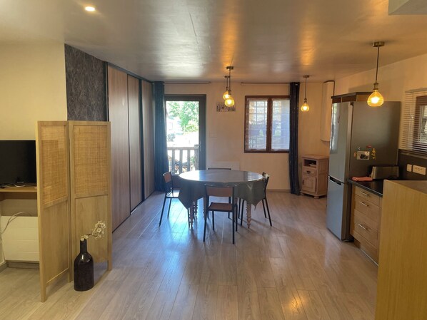 A modern kitchen with a dining area, wooden cabinets, a refrigerator, and a window with curtains. - Apartment in the center of Puy-Saint-Vincent, in the Ecrins mountains (Puy-Saint-Vincent)
