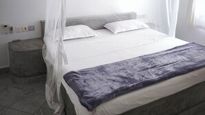 A bed with a canopy, a bedside table, and a power outlet on the wall. - 2-bed apartment Malindi Kenya Direct beach location (Malindi)
