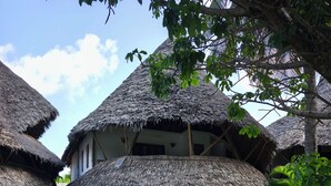 A traditional thatched-roof building with a stone pathway leading to it, surrounded by lush greenery. - 2-bed apartment Malindi Kenya Direct beach location (Malindi)