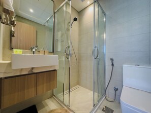 Un baño moderno con ducha de vidrio, lavamanos con espejo e inodoro.